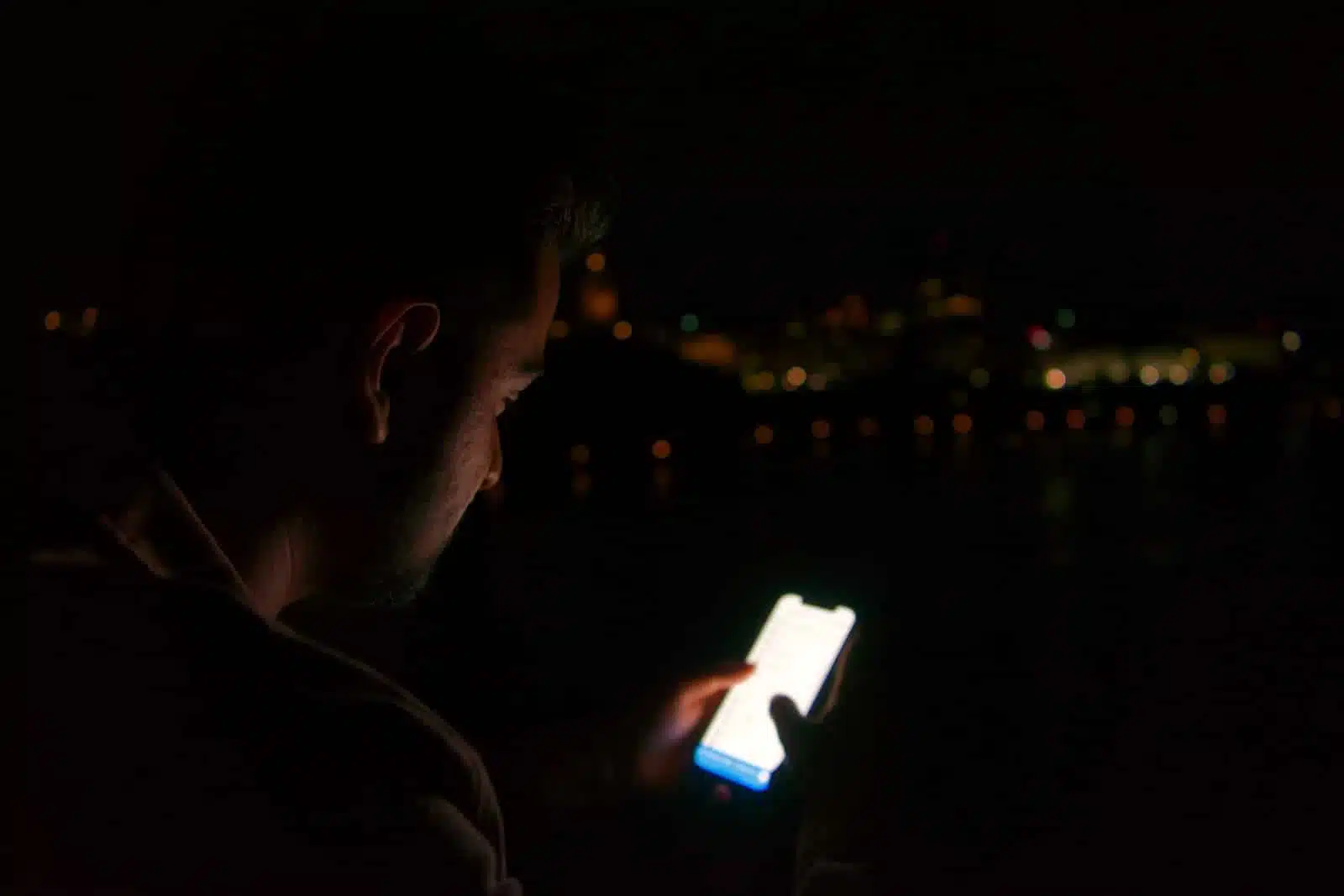 man in black shirt holding white smartphone