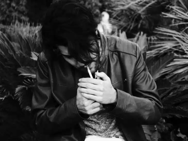 grayscale photo of man holding lighter