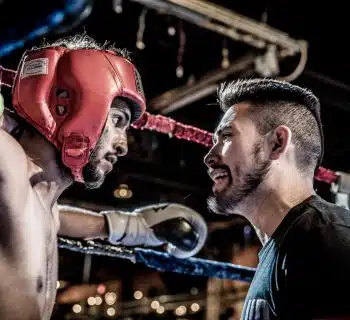 man in black talking to boxer inside ring