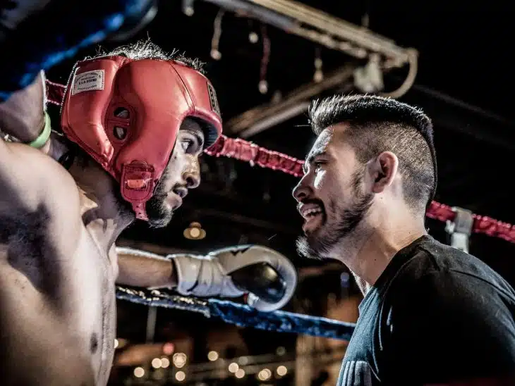 man in black talking to boxer inside ring